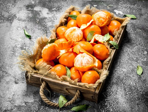 Fresh tangerines on a wooden tray on a rustic background