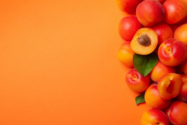 Fresh tasty apricots on orange background, top view