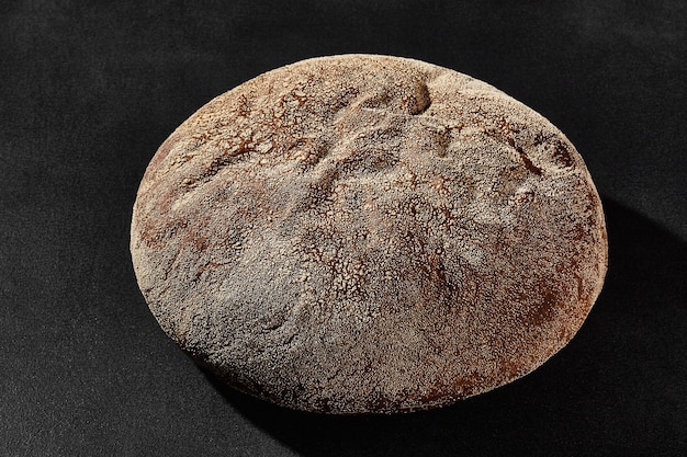 Fresh tasty baked round dark bread sprinkled with flour