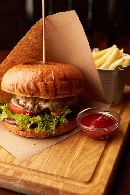 Fresh tasty beef burger with french fries on wooden table in pub