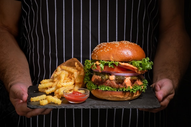 Fresh tasty burger and french fries hold in hands .Close up.