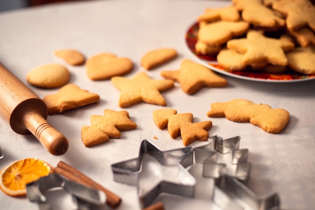 Fresh tasty cookies in different shapes near rolling pin and metal forms on the table