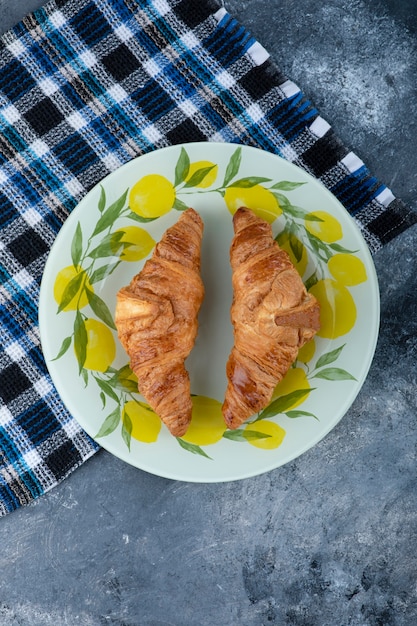 Fresh and tasty croissants in a plate placed on stone table 