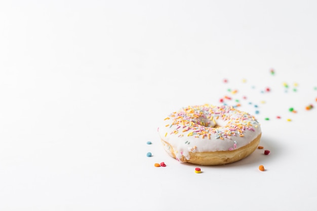 Fresh tasty donut and sweet multicolored decorative candy on a white background. Bakery concept, fresh pastries, delicious breakfast.