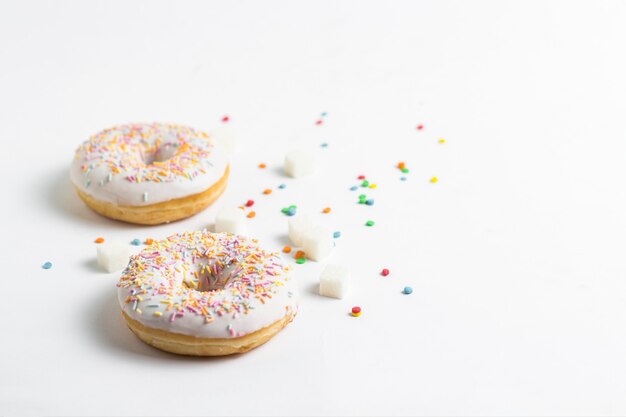 Fresh tasty donuts and sweet multicolored decorative candy on a white background. Bakery concept, fresh pastries, delicious breakfast.