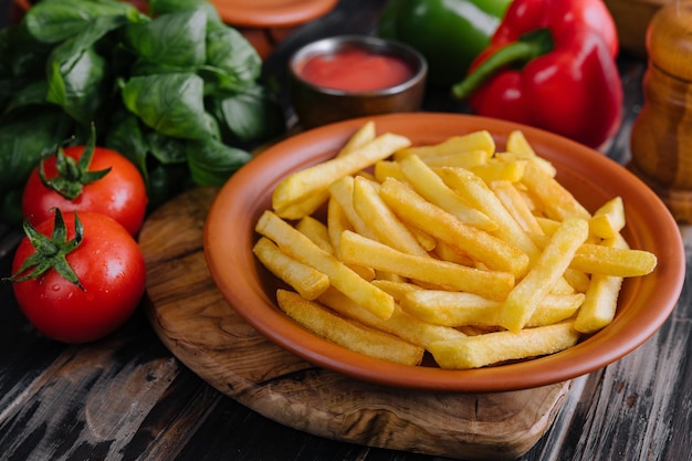 Fresh tasty french fries and red sauce on a wooden cutting board