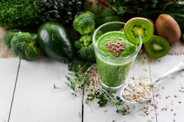 Fresh and tasty green smoothie with ingredients on wooden surface