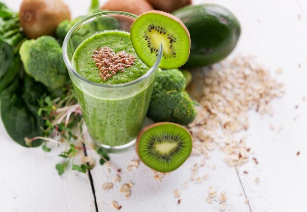 Fresh and tasty green smoothie with ingredients on wooden surface