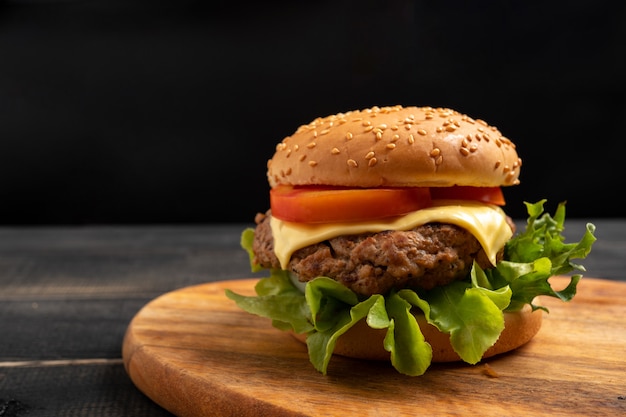 Fresh tasty homemade hamburger with fresh vegetables on a cutting board.