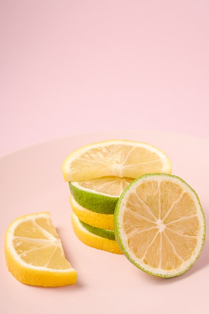 Fresh tasty lemon and lime citrus fruits slices stacked on pink plate