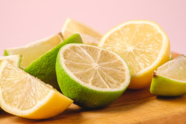 Fresh tasty lemon and lime citrus fruits slices on wooden cutting board