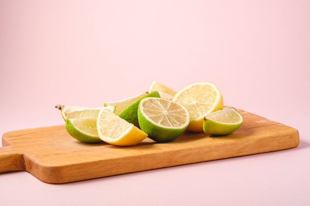 Fresh tasty lemon and lime citrus fruits slices on wooden cutting board