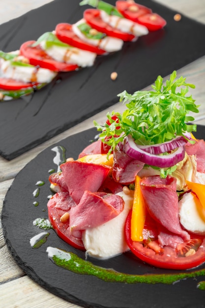 Fresh Tasty Persimmon salad with arugula, parma ham, olive oil and herbs. autumn, winter healthy food