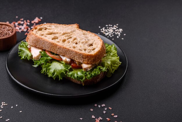 Fresh tasty sandwich with chicken tomatoes and lettuce on a black plate