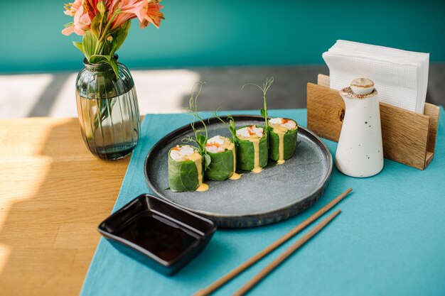 Fresh tasty sushi rolls with green leaves salmon and juicy sauce on the served table at the sushi restaurant with beautiful contrast lightning