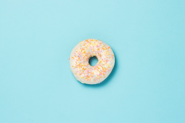 Fresh tasty sweet donut on a blue background. Fast food concept, bakery, breakfast.