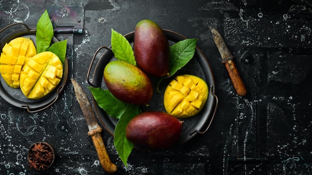 Fresh tasty sweet mango with leaves on old wooden dark background Rustic style Top view Tropical fruits