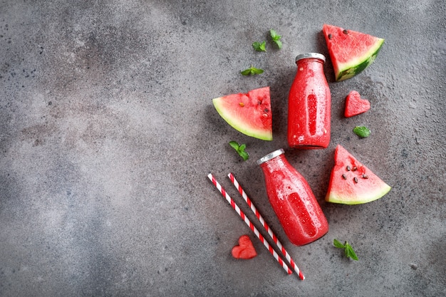 Fresh tasty watermelon smoothie in glass bottles on stone background. Top view. Copy space.