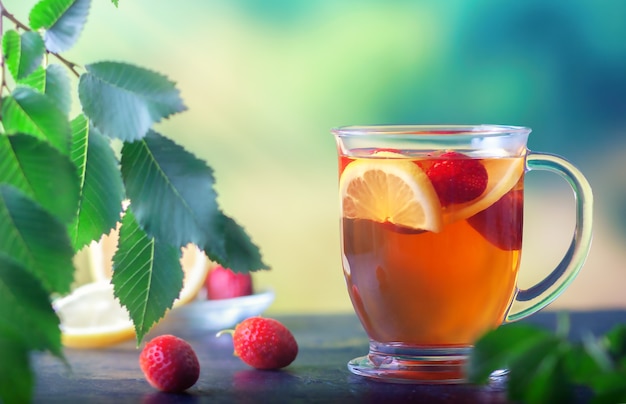 Fresh tea with lemon and strawberries in a large glass cup