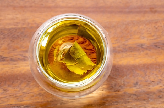 Свежий чай с чайным листом в воде на деревянном фоне