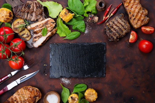 Photo fresh three types of grilled steak (chicken, pork, beef) on slate plate with herbs,