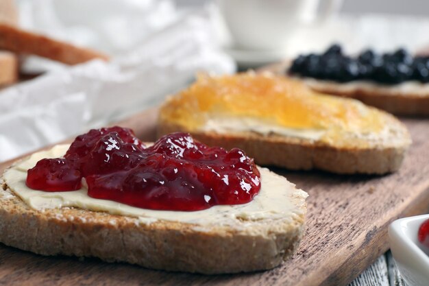 Fresh toast with butter and different jams on table close up