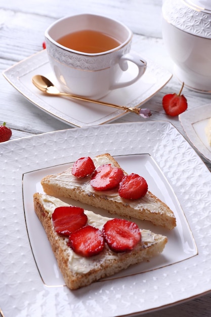 Свежий тост с домашним маслом и свежей клубникой на тарелке на деревянном фоне