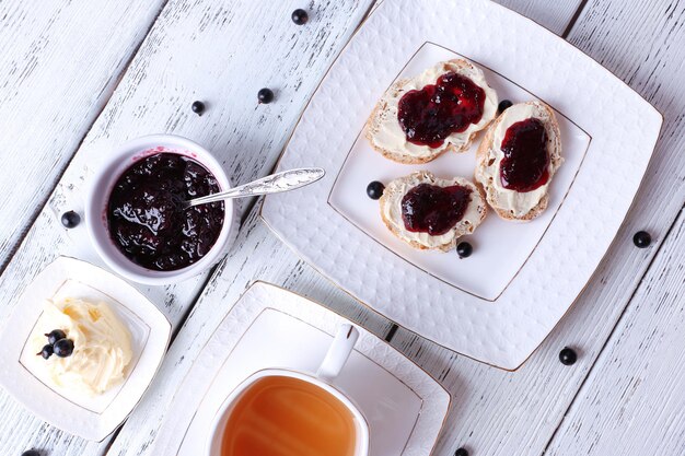 Fresh toasts with homemade butter and blackcurrant jam on wooden background