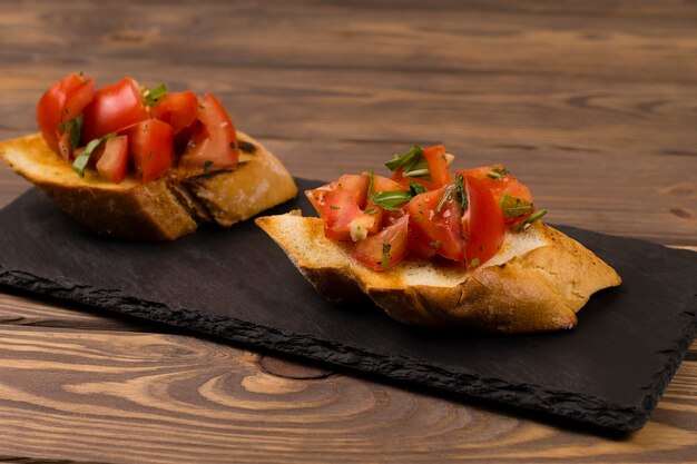 Fresh tomato bruschetta. italian appetizer with basil on wooden background.