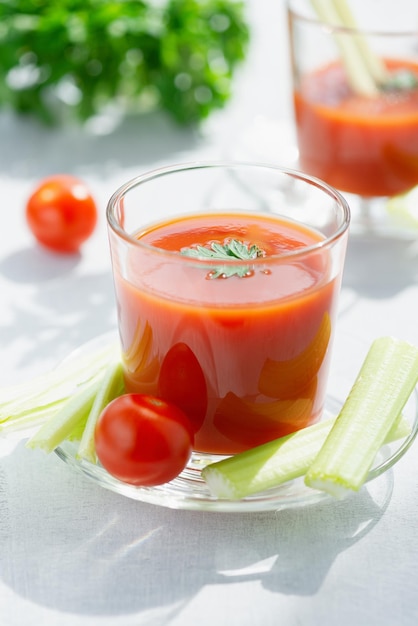 Fresh tomato juice Tomato juice is poured into a transparent glass with parsley and celery stems