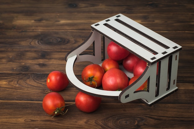 Foto i pomodori freschi vengono versati da una scatola su un tavolo di legno.