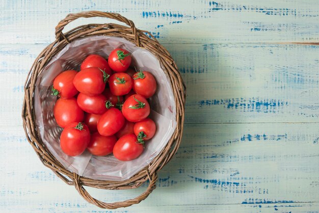 Fresh tomatoes in a basket on a wooden background