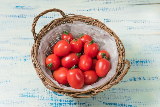 Fresh tomatoes in a basket on a wooden background