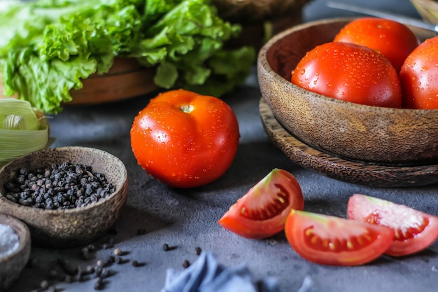 fresh tomatoes in a bowl, around vegetables, carrot, black pepper, corn, broccoli. Slice tomatoes. Harvesting tomatoes. 