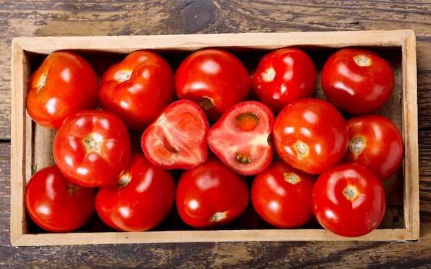 Foto pomodori freschi in una scatola sulla tavola di legno