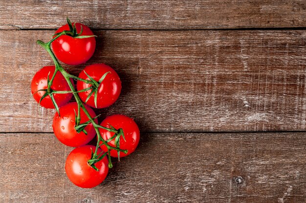 Fresh tomatoes on a branch on a textured wooden