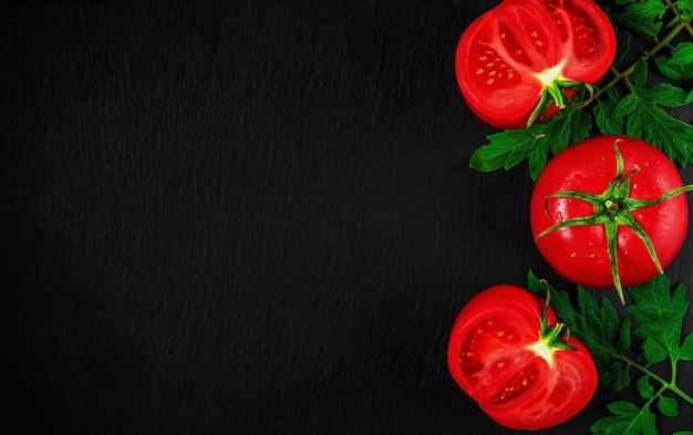 Fresh tomatoes cut in half on a black stone surface