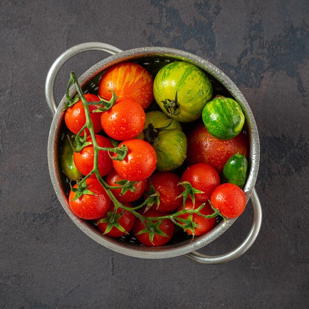 Fresh tomatoes on dark background in sieve