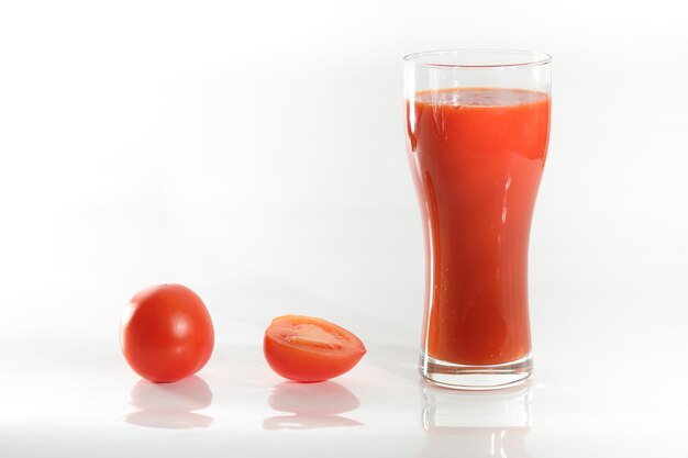 Fresh tomatoes and a full glass of tomato juice isolated.