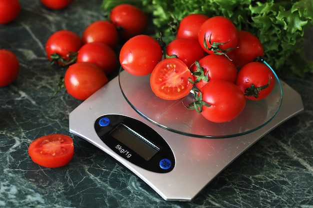 Fresh tomatoes on kitchen scales weighing and measuring