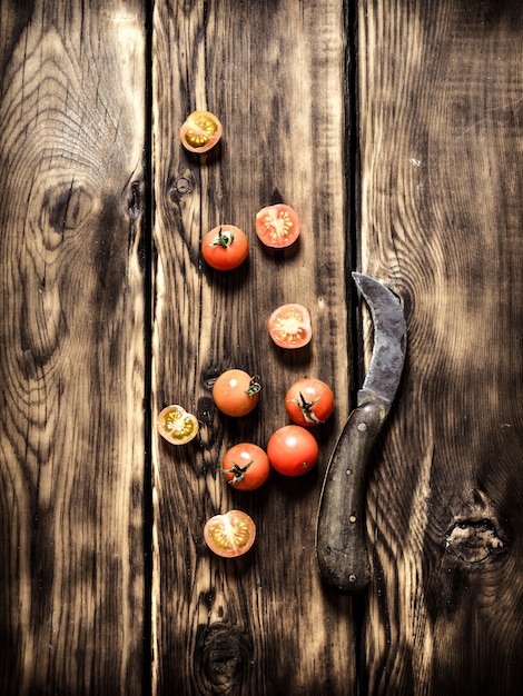 Fresh tomatoes and an old knife. On wooden background.