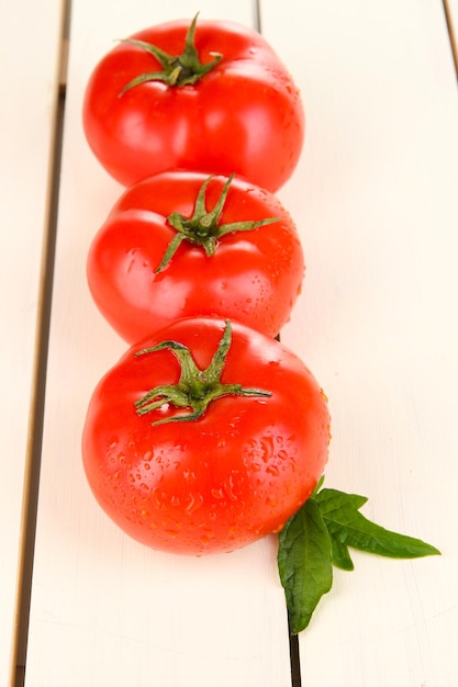 Fresh tomatoes on white wooden background