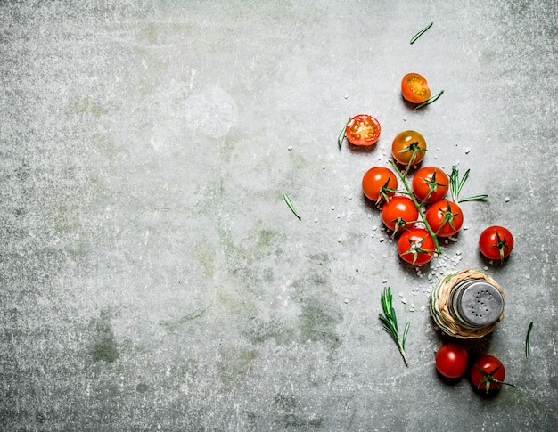 Fresh tomatoes with salt and rosemary. On a stone table.