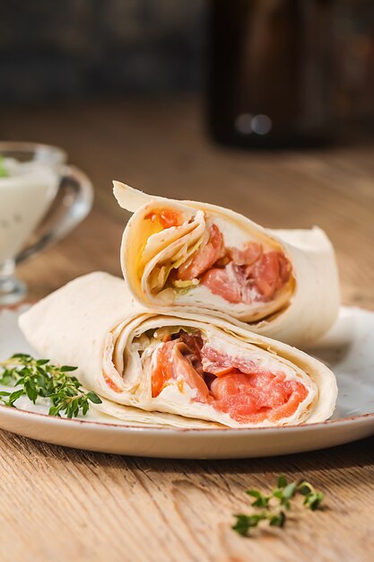 Photo fresh tortilla wrap with vegetables and salmon on plate