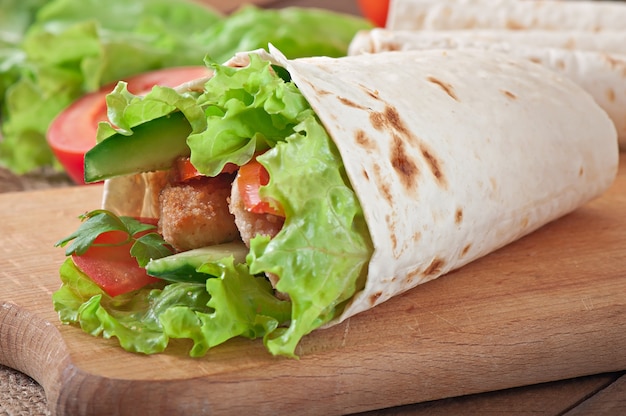 Photo fresh tortilla wraps with chicken nuggets and vegetables on plate