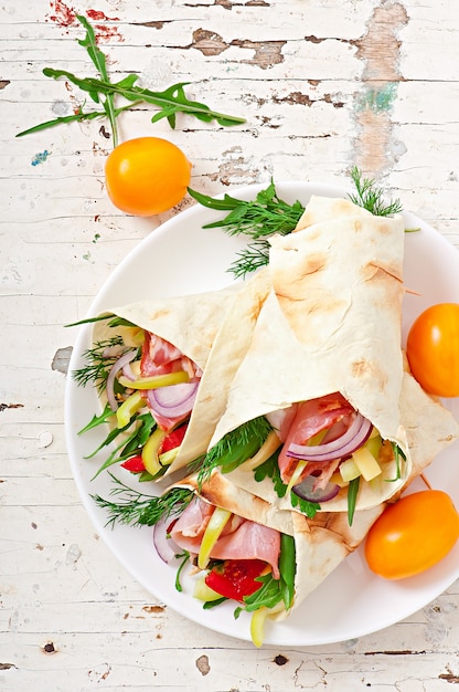 Fresh tortilla wraps with meat and vegetables on plate