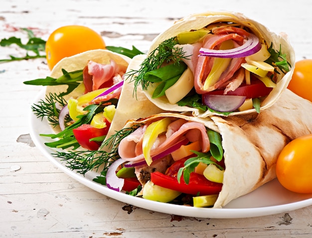 Fresh tortilla wraps with meat and vegetables on plate