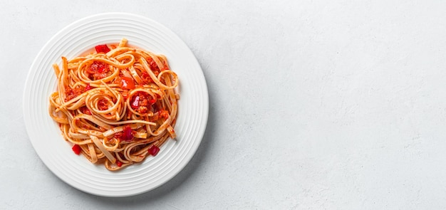 회색 배경에 토마토 소스를 곁들인 링귀니를 곁들인 신선한 전통 이탈리아 파스타