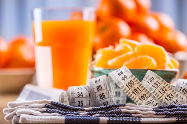 Fresh tropical fruit and measure tape Tangerines peeled tangerine and tangerine slices on a table