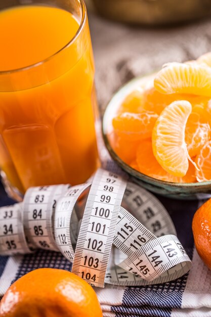 Fresh tropical fruit and measure tape Tangerines peeled tangerine and tangerine slices on a table